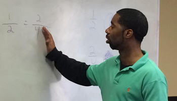 man working out math on a white board